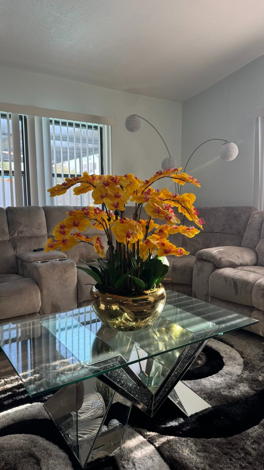 Kaskadierende gelbe Orchideen in einer goldfarbenen Edelstahlvase